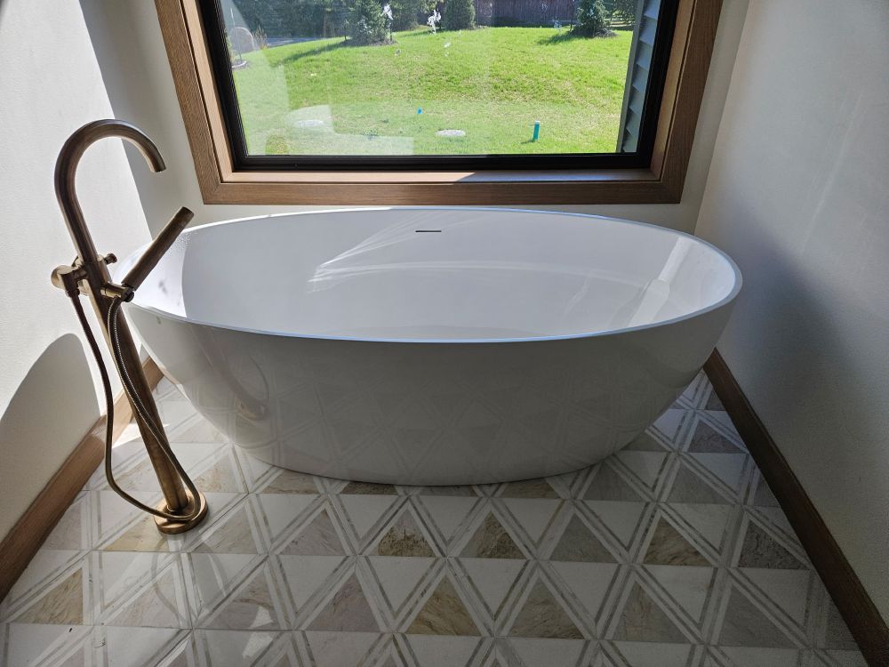 White freestanding bathtub with brushed gold floor-mount tub filler